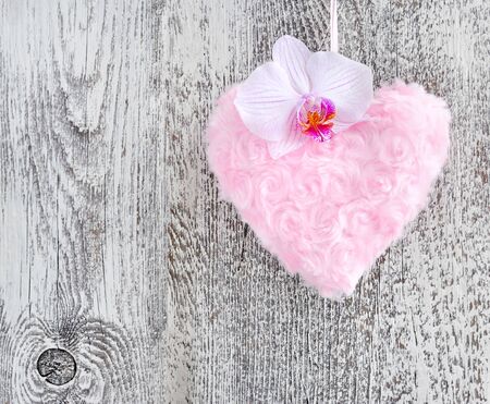 Fur pink heart with a flower orchid on wooden backgroundの写真素材