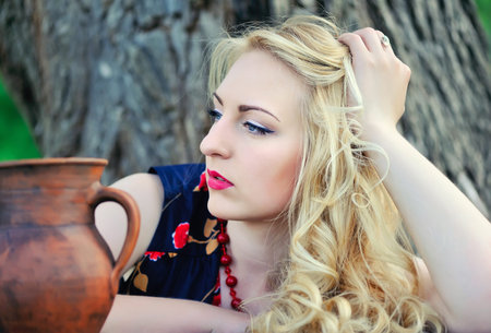Portrait of a beautiful blonde woman with a ceramic jugの写真素材