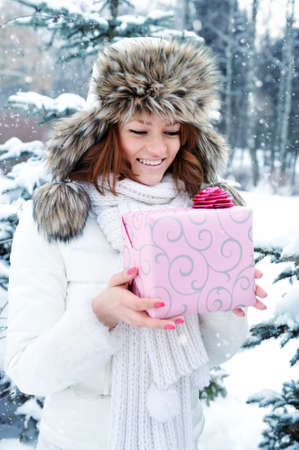A young girl is with a gift in winter parkの写真素材