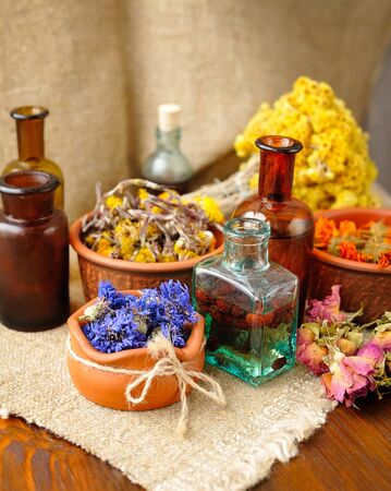 Healing herbs and tinctures in bottles on sackcloth, dried flowers, herbal medicineの写真素材