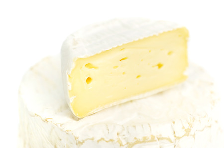 Round camembert cheese with a piece on white backgroundの写真素材