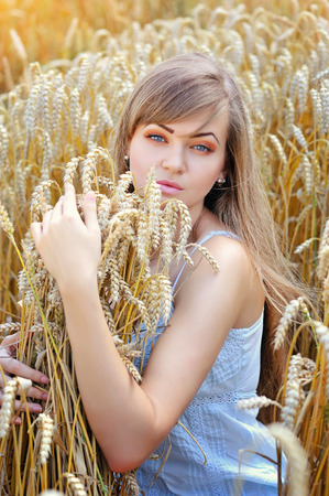 Young beautiful woman in golden wheat fieldの写真素材