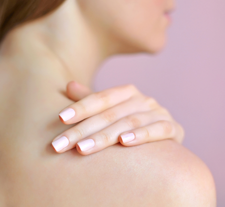 Beautiful woman with hand on shoulder. Focus is on a handの写真素材