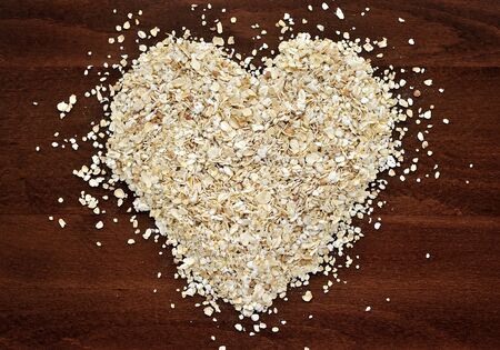 Heart shape made from oat flakes on dark wooden tableの写真素材