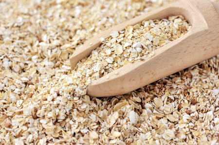 Oat flakes in wooden scoop, close-up