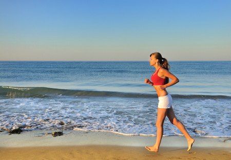 Beautiful girl running on beach at morningの写真素材