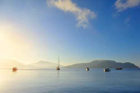 Beautiful morning seascape with boats and mountains in the backgroundの写真素材