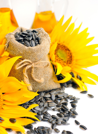 Small bag with sunflower seeds on a background of flowers and a bottle of sunflower oilの写真素材