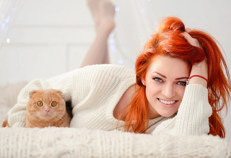 Beautiful young woman with red cat. The concept of Christmas. Christmas sunny morning.の写真素材