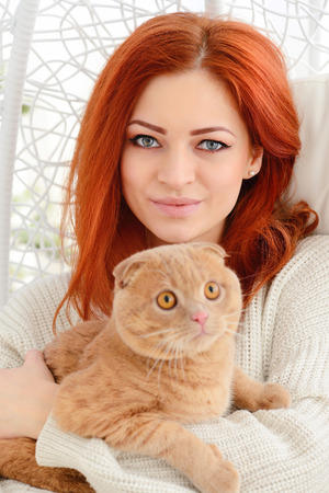 Beautiful young woman with red cat. Sunny morningの写真素材