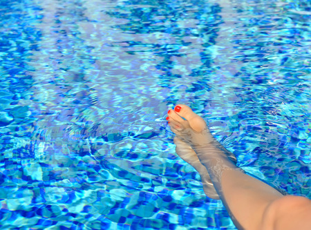 Woman feet in swimming pool on a hot summer dayの写真素材