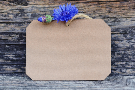 Paper tag with fresh cornflowers (Centaurea cyanus) on wooden tableの写真素材