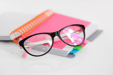 Eye glasses with pink spiral notebook on white backgroundの写真素材