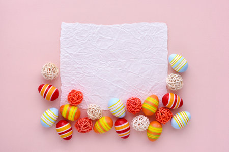 Colorful easter eggs and ribbons on a pink background with empty space. Top view