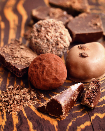 Handmade chocolate candies and pieces of chocolate on wooden backgroundの写真素材