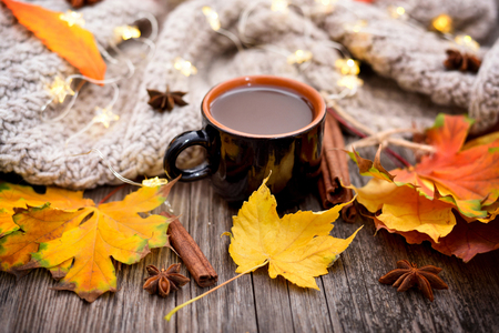 Autumn composition. Fall leaves, cup of coffee and scarf on old wooden background.の写真素材