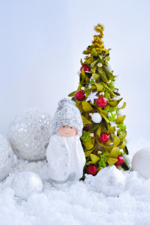 Decorative little boy figure and christmas tree with festive decorations Ð¾n the snow. New Year greeting card.の写真素材
