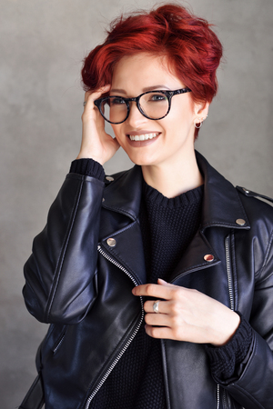 Portrait of a beautiful young red-haired woman wearing elegant glasses. Optics styleの写真素材