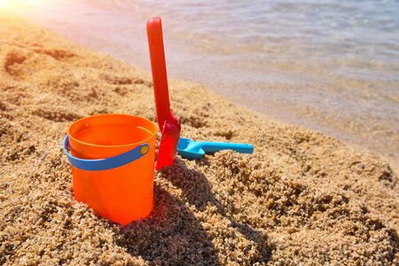 Bright plastic Ñhildren's beach toys - bucket and shovels on sand near seaの写真素材