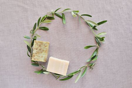 Circle frame of olive branches and handmade soap bars on gunny background. Top view.の写真素材
