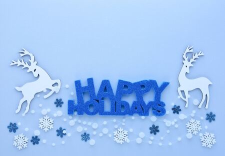 Christmas or New Year greeting card. Greeting "Happy Holidays", deers  and snowflakes on pastel blue background. Flat lay, top view, copy spaceの写真素材