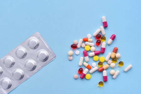 Assorted pharmaceutical medicine pills, tablets and capsules over blue background. Top view