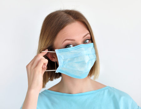 Girl puts a medical face mask for protection against infection. Healthcare and medical concept.