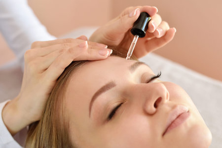 Closeup of beautiful woman receiving serum for skin moisturizing from pipette. Beauty, skincare...