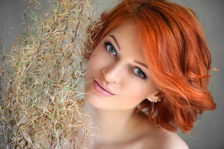 Portrait of young beautiful redhaired woman with dried flowersの写真素材