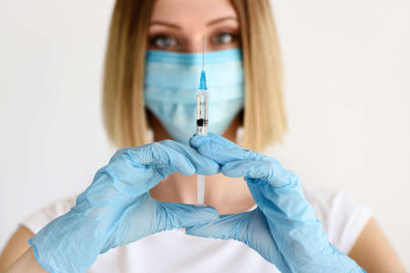 Nurse or doctor in a mask and medical gloves with an injection in his hands. Medical and healthcare concept.の写真素材