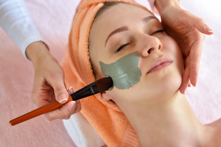 Face peeling mask, spa beauty treatment, skincare. Woman getting facial care by beautician at spa...