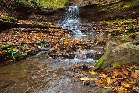 Beautiful landscape with a waterfall in the autumn forestの写真素材