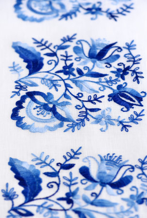 Hand embroidery stitch on a thin canvas. Blue floral ornament on a white background. Art and craft...
