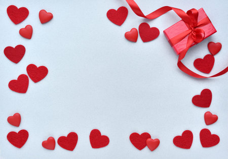 Valentines day background. Red gift box with ribbon and hearts on a pastel blue background. top view