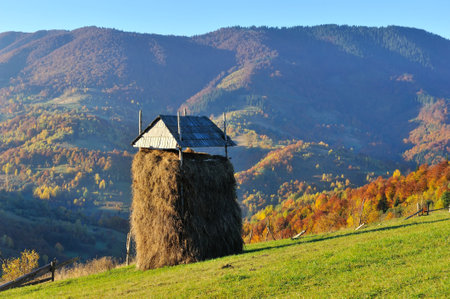 Beautiful autumn mountain landscape in the morning light. Haystack on the background of autumn slopesの写真素材