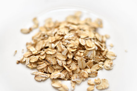 Dry rolled oat flakes oatmeal on white plate