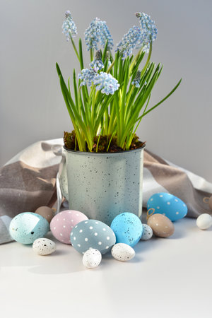 Easter eggs and light blue muscari flowers in cup on a white table. Easter still lifeの写真素材