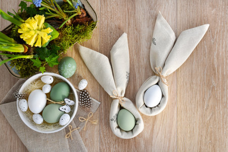 Easter eggs in a white bowl on linen cloth and spring primroses in a pot. Easter eggs wrapped in a...