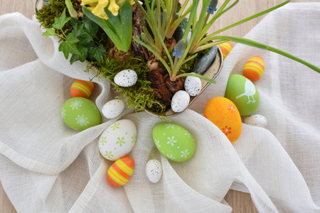 Colorful easter eggs on linen cloth and spring primroses in a pot. Easter still lifeの写真素材