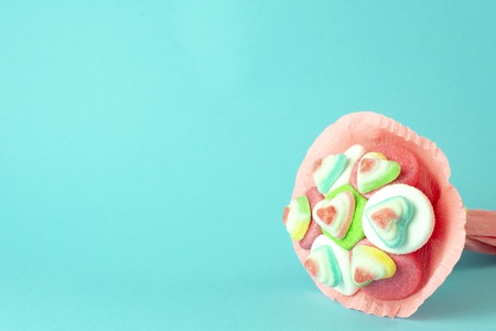 bouquet of marmalade and sweets in a pink box on a turquoise background, top view, place for textの写真素材