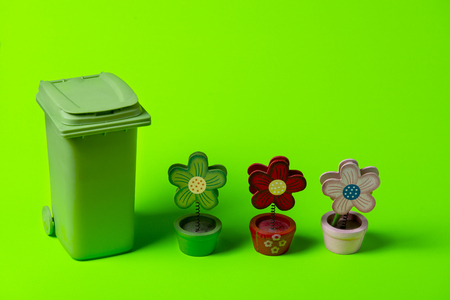 Green trash can with flowers on a green background.の写真素材
