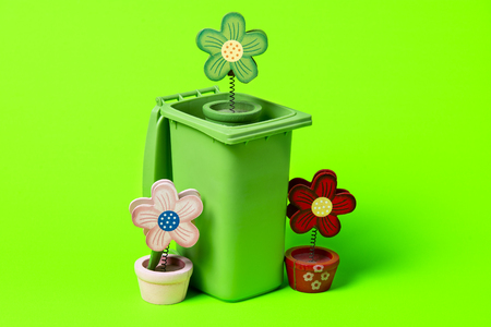Green trash can with flowers on a green background.の写真素材