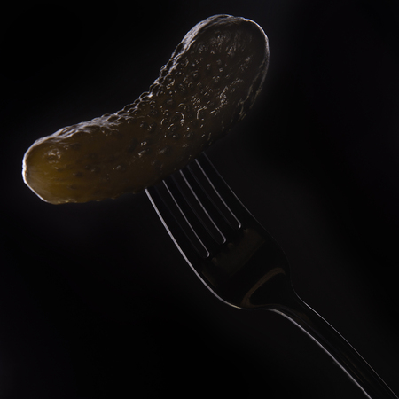 Salted cucumber on a fork on a black backgroundの写真素材