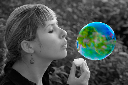 Girl blowing a soap bubble in the shape of a planet. Planet Earth. Earth. Conceptual image. Ecological conceptの写真素材