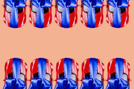 Many red cars with a blue bow as a gift on a colored background. Space for text, background.の写真素材