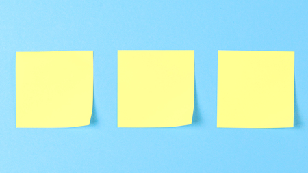 Blank yellow sticky notes on a blue background, concept of business work. Yellow memo stickers on blue wall. Mock-up.の写真素材