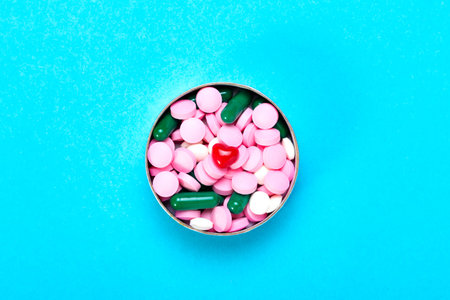 Small red heart with multi-colored pills on a blue background
