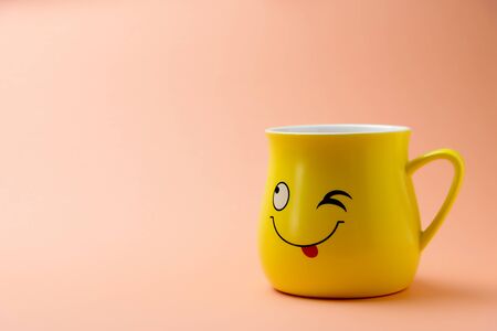 Yellow cup with a winking smile on a colored backgroundの写真素材