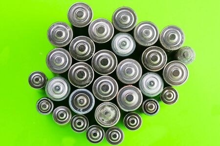 Use AA and properly dispose of batteries that are toxic to the environment and soil against a green background. The concept of technologies for processing hazardous and recyclable substances.の写真素材