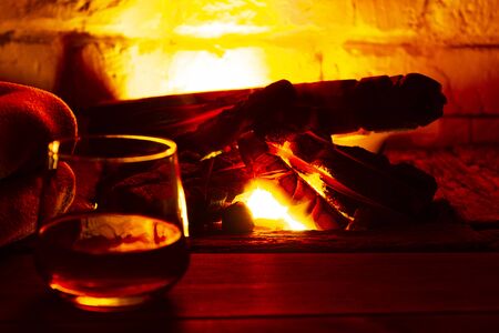 Glass of alcoholic drink wine in front of warm fireplace. Magical relaxed cozy atmosphere near fire.の写真素材